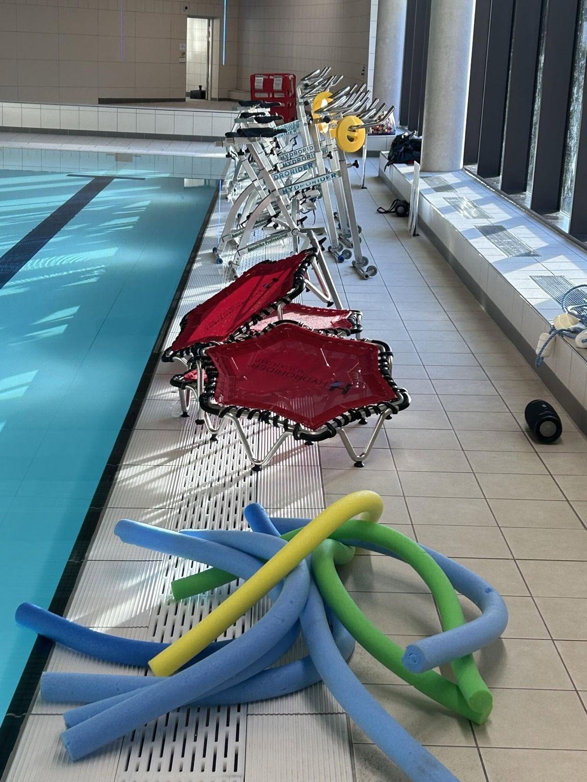 Bikes, water trampolines and noodles set up poolside for a circuits session